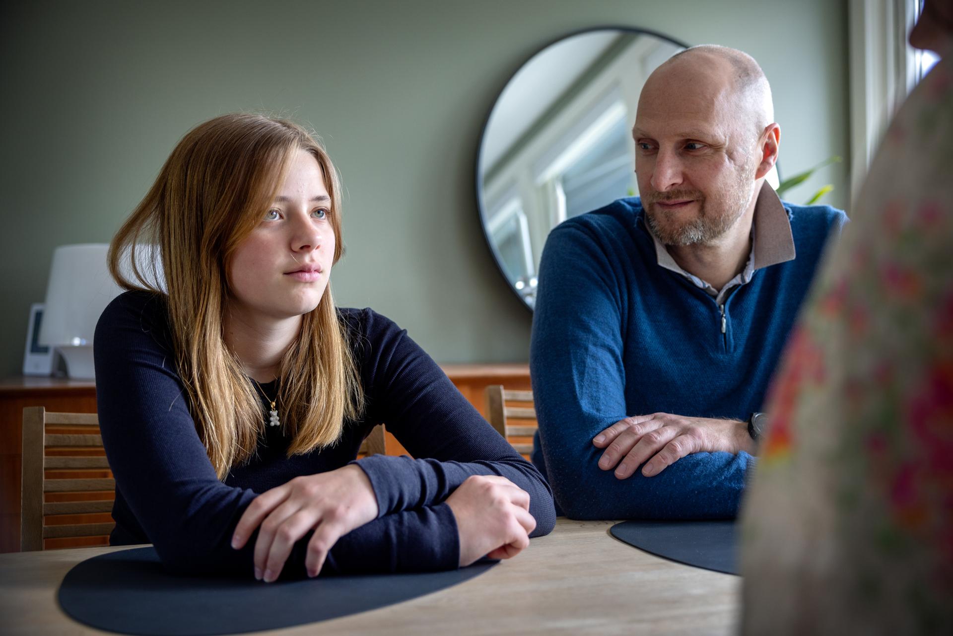 Far snakker med en ungdom foran en skjerm