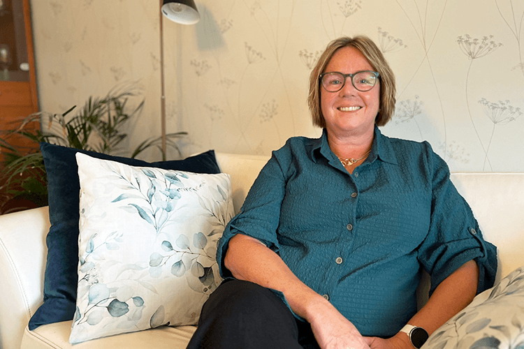 Marit sitter på en lysfarget sofa