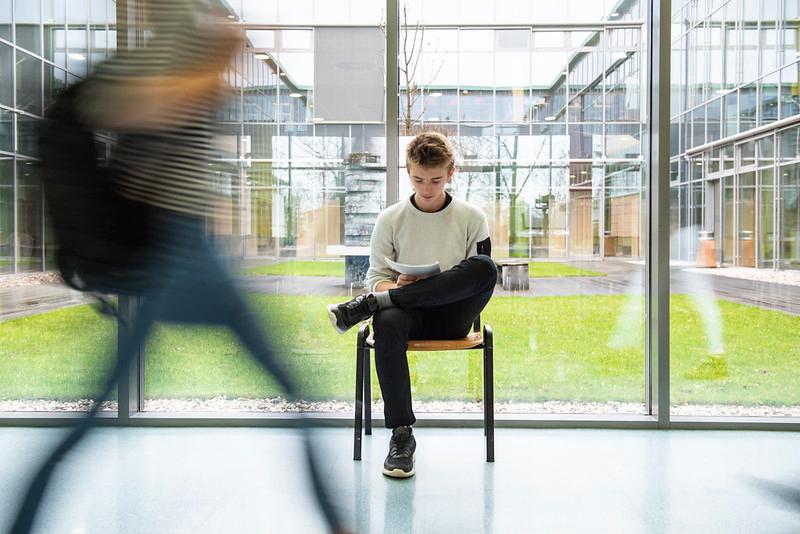 Tenåring sitter på stol og leser