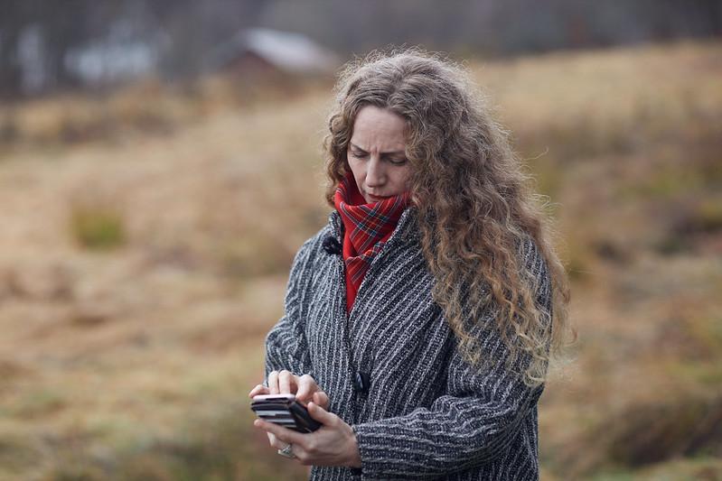 Kvinne ser på mobilen mens hun er utendørs