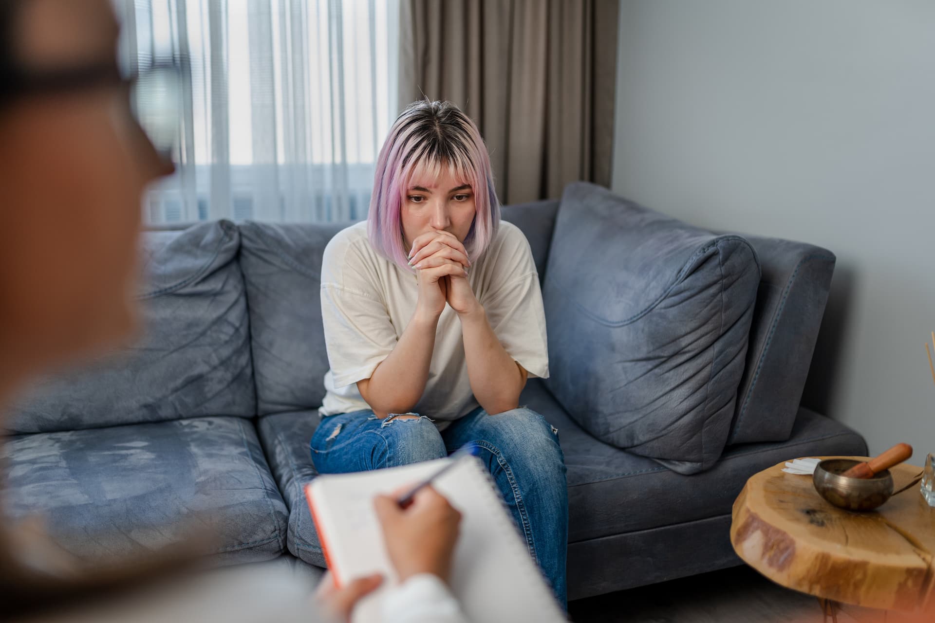 Et ungdom som sitter i en sofa. Foran henne er det en person som holder en notatblokk.