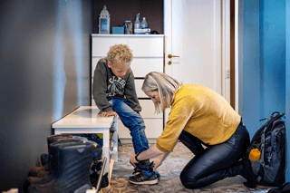 Barn får hjelp med sko av mamma.