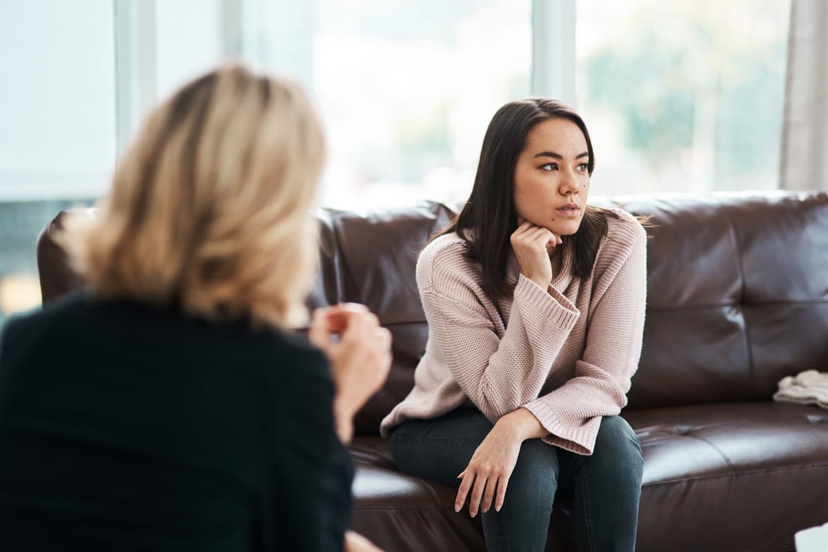Person sitter i sofa i samtale med en annen.