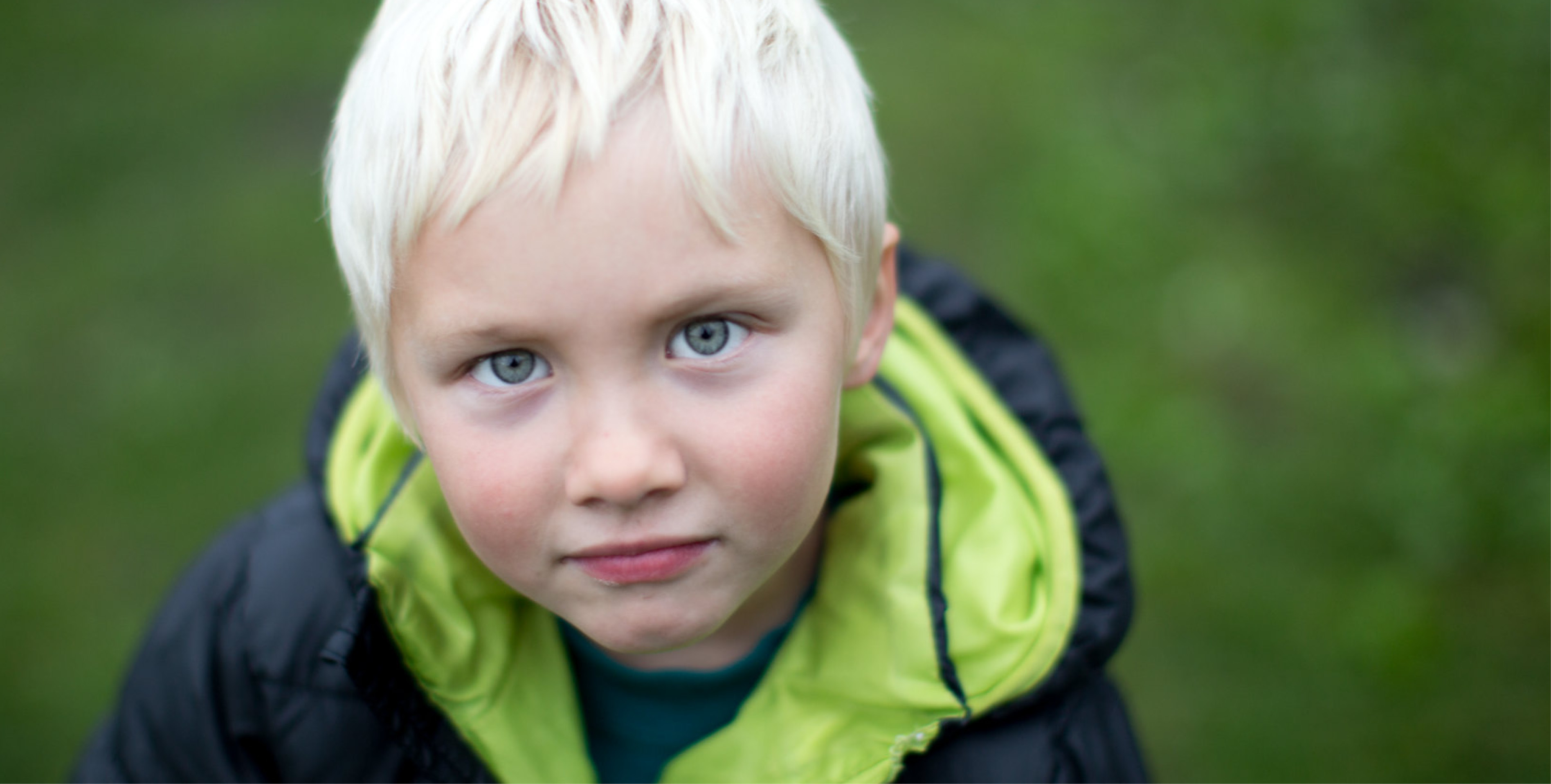 Ung gutt på omtrent fem år med lyst hår ser inn i kamera med alvorlig eller avslappet blikk