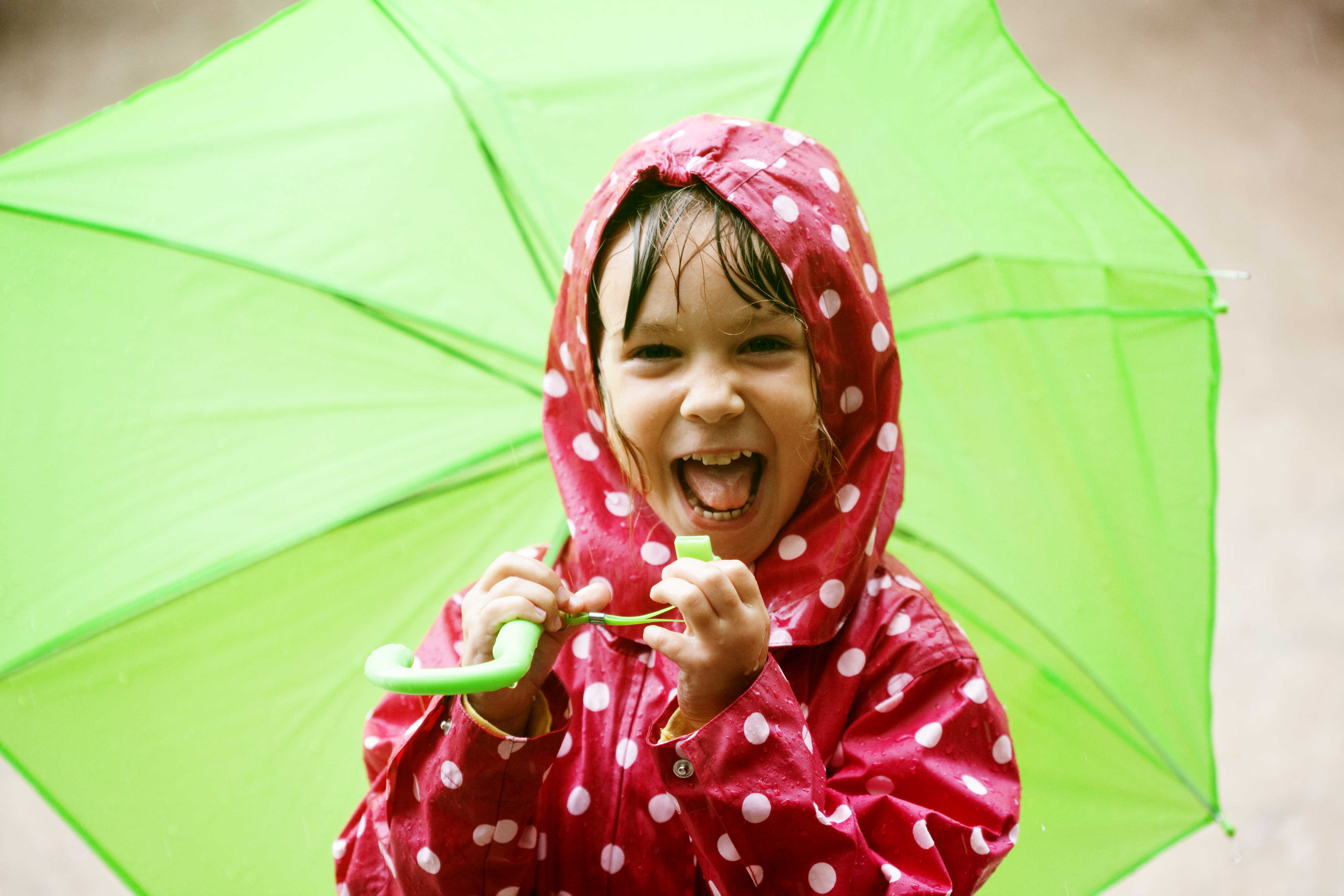 jente med grønn paraply lager grimaser